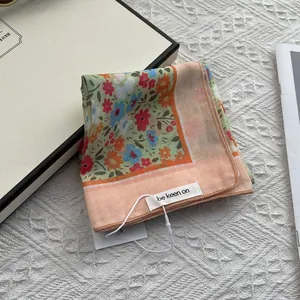 Detailed shot of a floral scarf with orange border and small flower pattern design