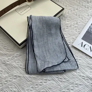 Detailed view of striped linen scarf texture and rolled edges on a beige gift box