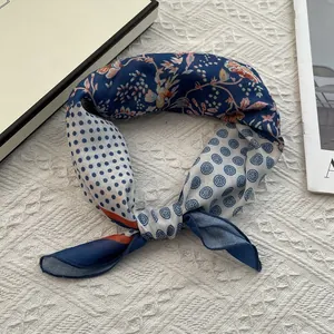 Détail d'un foulard en soie noué avec des motifs à pois et des fleurs classiques