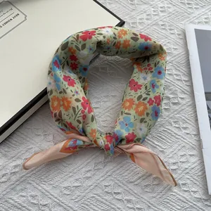 Detailed close-up of a knotted floral silk scarf with small red and orange flowers