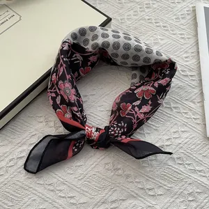 Gros plan d'un foulard en soie rétro avec motifs floraux sur un fond de textile en dentelle