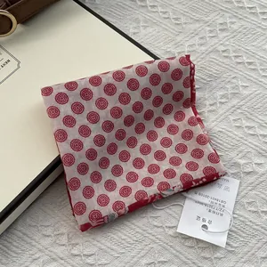 Détail d'un foulard en coton plié à pois fleuris rouges avec étiquette produit