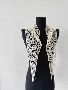 Detailed close-up of cream white daisy crochet lace shawl on a black mannequin