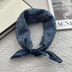 Blue geometric floral scarf in cotton linen blend displayed on textured quilted background