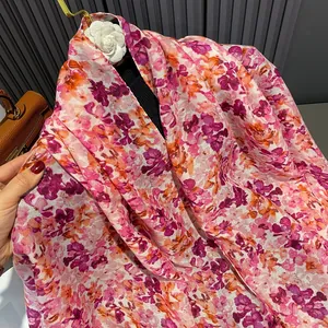 Detail showing the light floral pattern and soft cotton texture of the yellow-green scarf