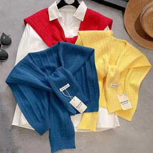 Trio of colorful hollow knit shawls in red, blue, and yellow layered on a white shirt