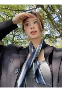 Detalle de bufanda estrecha a rayas azul oscuro y verde con una chaqueta negra