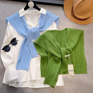 Flat lay of hollow knit shawls in blue and green with a white shirt and accessories