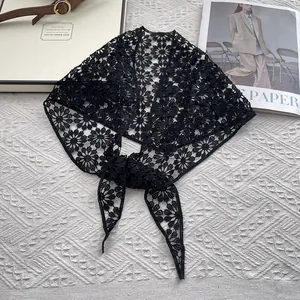 Detailed view of black floral lace crochet pattern on a sheer cotton triangular shawl