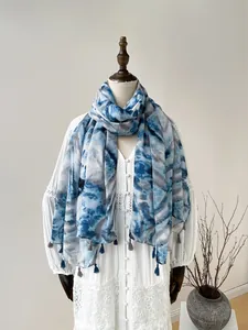 Detail of blue and grey tie-dye scarf with decorative tassels on minimalist display