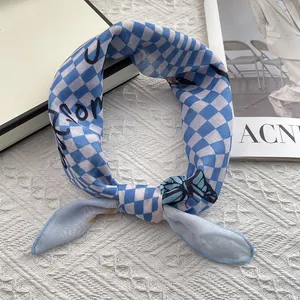 Detail of blue checkerboard silk scarf with butterfly print on a textured background