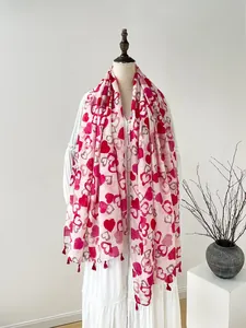 Detail of red heart prints on a soft pink linen scarf with small red tassels