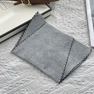 Detail of checkered cotton scarf with black scalloped embroidery edge and soft texture