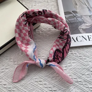 Detail of pink checkerboard silk scarf featuring black butterfly prints and artistic graffiti