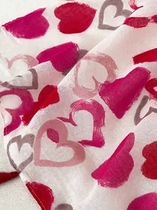 Close-up of cotton linen scarf with red heart prints and delicate fringe details
