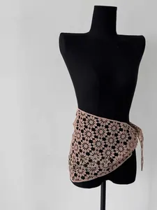 Detail of crochet floral lace shawl in pink with intricate hollow patterns and tie strings