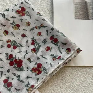 Dettaglio di un fazzoletto di lino a fiori rossi con bordo rifinito a punto overlock
