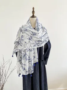 Detailed macro shot of the blue tassel edge and tree branch pattern on the white shawl