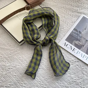 Detail of pure linen green plaid scarf with refined lock-stitch edges on a white background