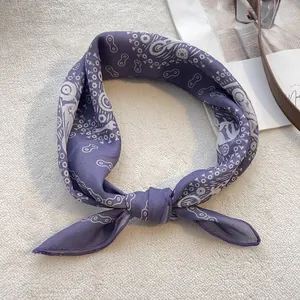 Detail of purple cotton scarf with floral chain print tied in a bow on soft fabric