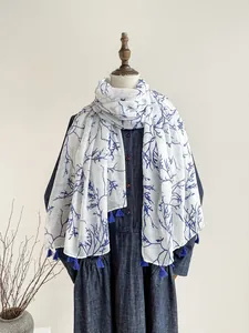 Detail of blue branch floral print on white scarf with matching fringe tassels