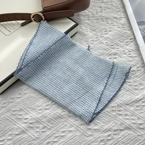 Detail of blue gingham cotton scarf featuring decorative scalloped edge and soft texture