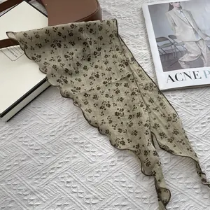 Close-up of olive green floral scarf with cotton linen texture and brown wavy edges