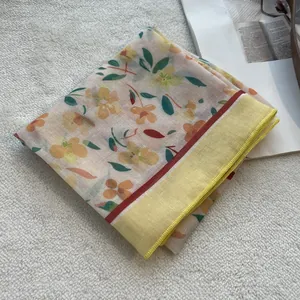 Detail of floral cotton square scarf with yellow flowers and stitched edge on white fur