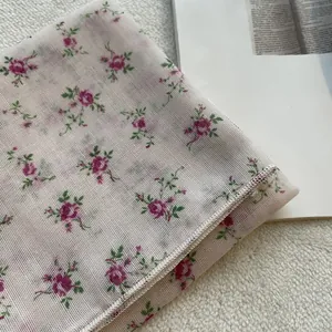 Dettaglio della stampa a rose rosa su tessuto a rete bianco con rifinitura dei bordi
