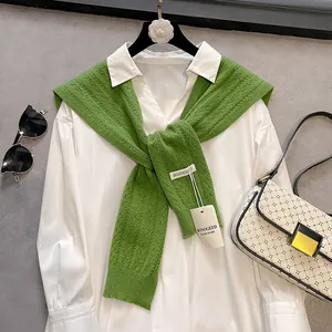 Detail of green hollow knit shawl with tie-knot and textured weave on white shirt