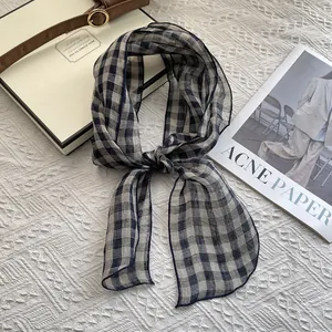 Close-up detail of the breathable linen texture and classic black and white plaid scarf pattern