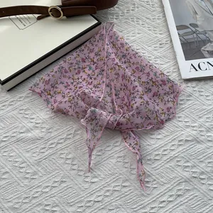 Détail d'un foulard triangle rose à fleurs en coton et lin avec ourlet surjeté fin