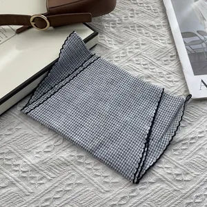 Detail of blue and white gingham cotton neckerchief with black wavy embroidered edges