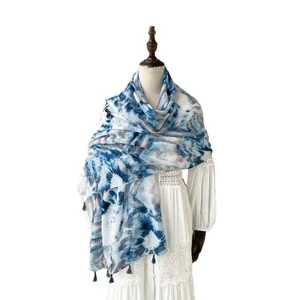 Tie-dye cotton linen scarf in blue and white with tassels for women worn on a white dress