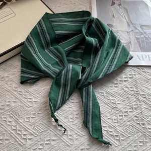 Detalle de bandana a rayas verde oscuro anudada con estilo sobre un fondo de tela blanca