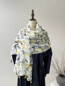 Détail d'une écharpe à motif citron avec des glands décoratifs jaunes et verts