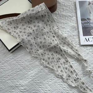 Detail of floral linen scarf with wavy edges on a stylish bag and magazine