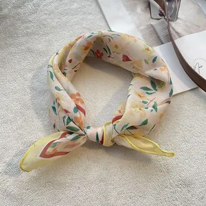Close-up of knotted floral cotton scarf with yellow hem on soft white background