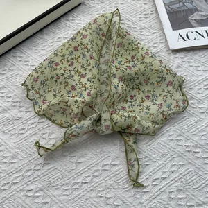 Gros plan du foulard triangle en coton et lin avec motif floral et finitions soignées