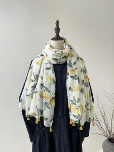 Détail d'une écharpe imprimé citron avec glands jaunes sur tissu de gaze léger