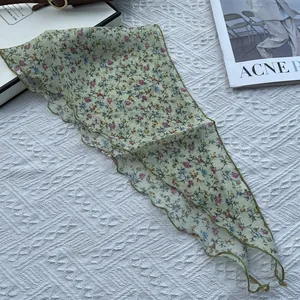 Gros plan du foulard triangulaire en coton lin à fleurs avec bords ondulés couture