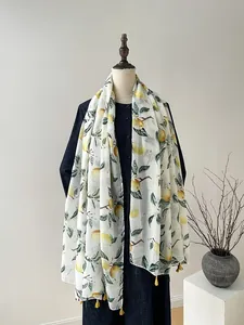 Détail d'une écharpe imprimé citron avec pompons, texture légère pour châle d'été
