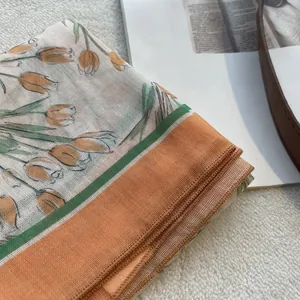 Close-up of cotton linen floral scarf with orange tulip print and green borders