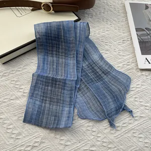 Detail of blue plaid skinny silk scarf on quilted fabric with elegant fashion accessories