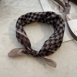 Detail van een vintage bruine geruite halsdoek geknoopt in een strik op zachte stof