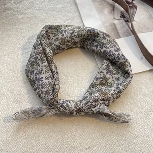 Dettaglio di un foulard annodato in cotone e lino con motivi floreali viola e gialli