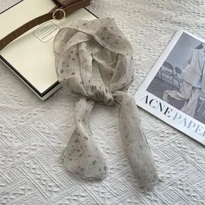 Close-up of pure linen scarf with black floral print on textured beige knit background