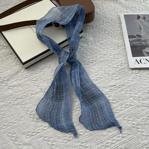 Close-up of lightweight blue plaid linen scarf with fine hemmed edges on white texture