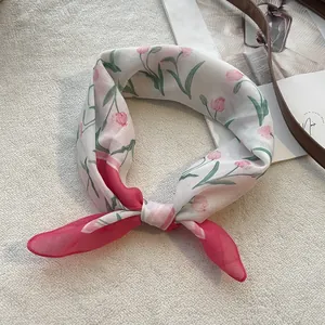 Close-up of a white cotton scarf with floral tulip patterns and pink sheer ends