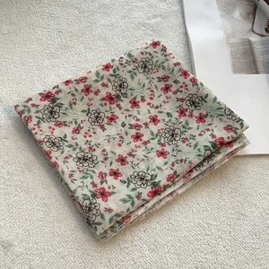 Dettaglio di un foulard in cotone lino beige con stampa floreale e bordo a punto sopraggitto